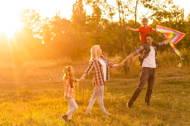 Szczęśliwy rodzinny ojciec matki i córek wypuszcza latawiec na przyrodę o zachodzie słońca