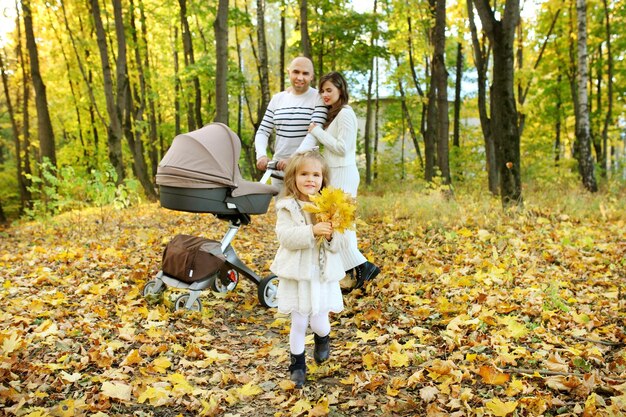 Szczęśliwy słoneczny dzień w jesiennym parku rodzice rodzinni rzucają żółte liście na dziecko i córkę