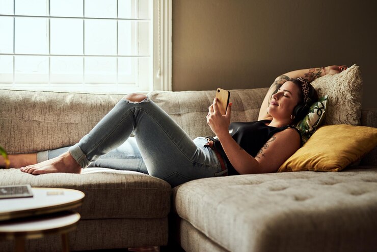 Zdjęcie szczęśliwy smartfon i kobieta z słuchawkami salon i chłodzenie z muzyką strumieniową i wygodne domowe dźwięk i spokój z czatem radiowym i osoba z mobilnym podcastem i odpoczynek w mieszkaniu