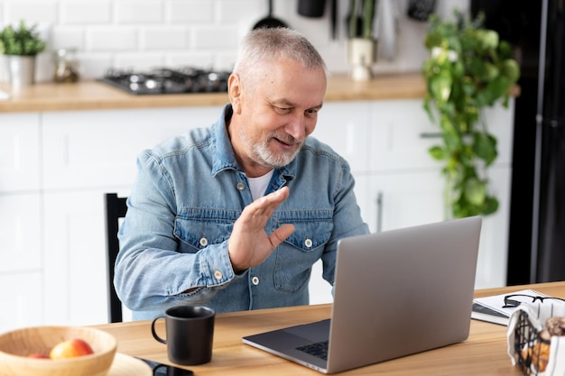 Szczęśliwy starszy mężczyzna rasy kaukaskiej siedzący w domu za pomocą laptopa do rozmowy wideo