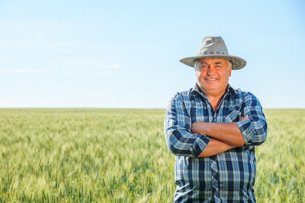 Szczęśliwy starszy rolnik stojący w polu