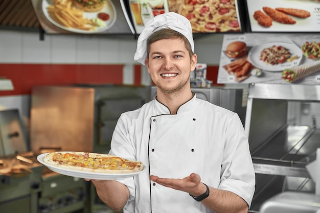 Szczęśliwy szef kuchni pokazuje tradycyjną włoską pizzę w kawiarni.