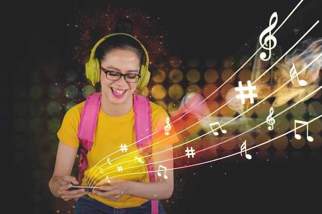Zdjęcie szczęśliwy uczeń słuchający muzyki za pomocą telefonu komórkowego