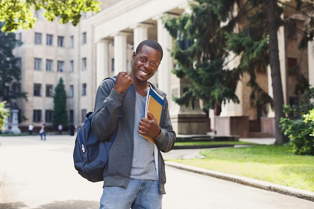 Szczęśliwy Udany Student Afro-amerykański Z Książkami, świętujący Zwycięstwo Na świeżym Powietrzu. Koncepcja Edukacji, Zwycięzcy I Osiągnięć, Miejsce Kopiowania