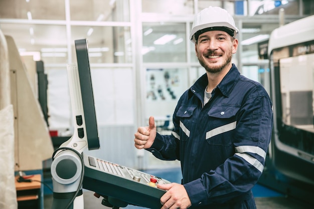 Zdjęcie szczęśliwy uśmiech kciuk w górę pracownik inżyniera pracuje z tokarką cnc w nowoczesnej fabryce metali