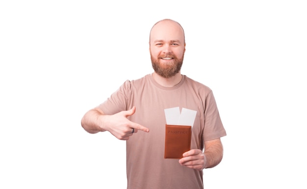 Szczęśliwy uśmiechający się młody człowiek z brodą, wskazując na paszport i bilety