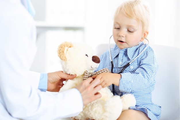 Zdjęcie szczęśliwy uśmiechający się pacjent dziecko w zwykłym oględzinach lekarskich. lekarz i pacjent w klinice. medycyna, koncepcje opieki zdrowotnej.