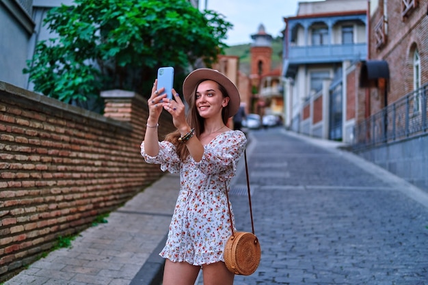 Szczęśliwy uśmiechający się piękny śliczny radosny młody podróżnik robi zdjęcie na aparacie telefonu podczas weekendu wakacyjnego podczas zwiedzania