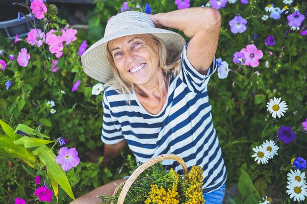 Szczęśliwy uśmiechający się starszy kobieta pozuje w letnim ogrodzie z kwiatami
