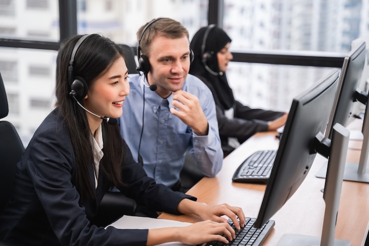 Zdjęcie szczęśliwy uśmiechnięty azjatykci kobiety centrum telefoniczne, operator z kolegą jest ubranym słuchawki pracuje na komputerze i opowiada z klientem z jej usługowym umysłem