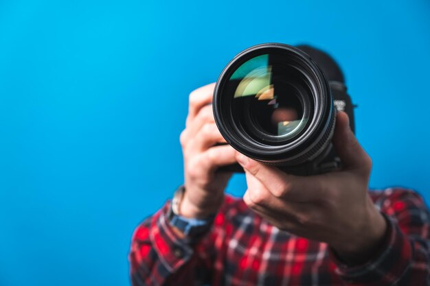 Zdjęcie szczęśliwy uśmiechnięty młody fotograf robi zdjęcia, sprawdzając ustawienia aparatu w studiu zdjęciowym