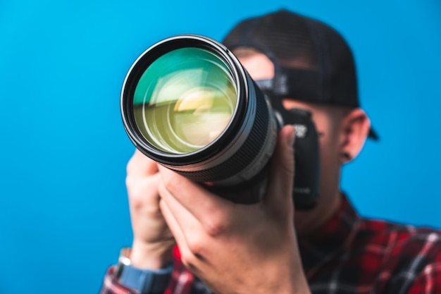 Zdjęcie szczęśliwy uśmiechnięty młody fotograf robi zdjęcia, sprawdzając ustawienia aparatu w studiu zdjęciowym