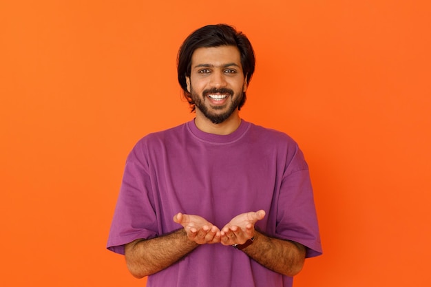 Szczęśliwy uśmiechnięty młody indyjski mężczyzna trzyma coś w dłoniach