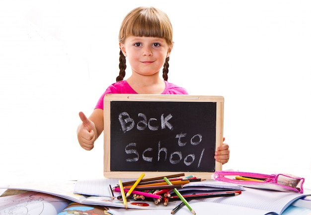 Szczęśliwy uśmiechnięty uczeń trzyma małą tablicę z tekstem „powrót do szkoły”