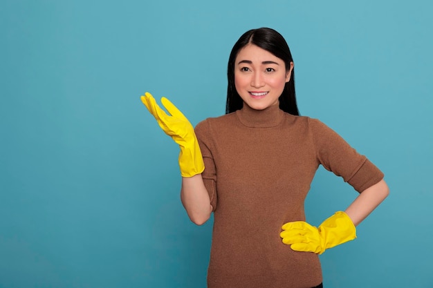 Szczęśliwy zadowolony i uśmiechnięty azjatycki kobieta gest ręką w żółtych gumowych rękawiczkach gest ręką, sprzątanie koncepcji domu, zadowolona, wesoła i roześmiana pielęgniarka