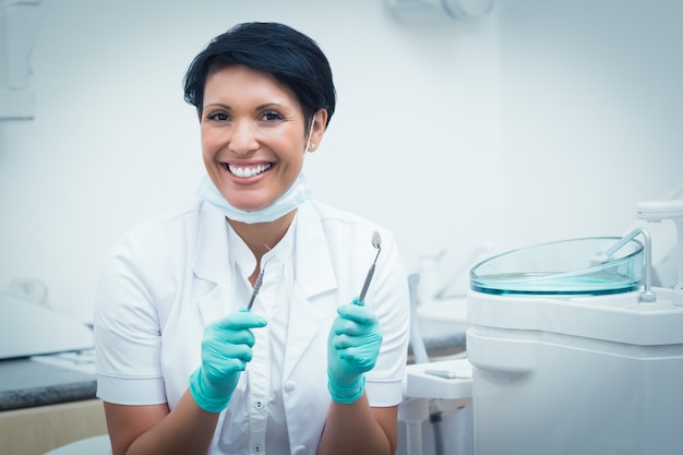 Szczęśliwy żeński dentysta trzyma stomatologicznych narzędzia