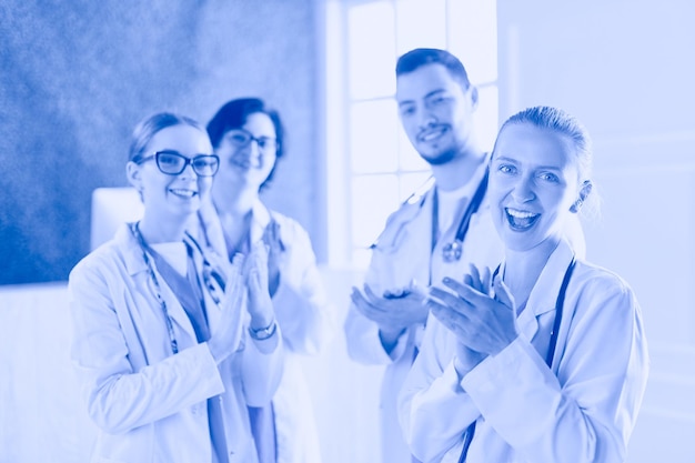 Zdjęcie szczęśliwy zespół medyczny składający się z lekarzy płci męskiej i żeńskiej, uśmiechniętych szeroko i podających kciuki z succ