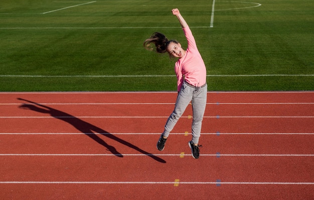 Zdjęcie szczęśliwy zwycięzca biegacz na zawodach świętować sukces sprinter wygrany na stadionie zwycięzca siłowni dziecko w szkole lekcja wychowania fizycznego czyste szczęście ona jest naprawdę szczęśliwa nastolatka jest mistrzem