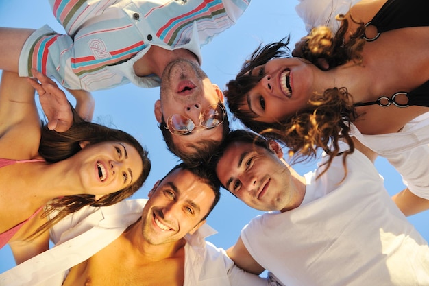 szczęśliwych młodych przyjaciół grupa przytulająca się do zabawy i świętowania na plaży o zachodzie słońca