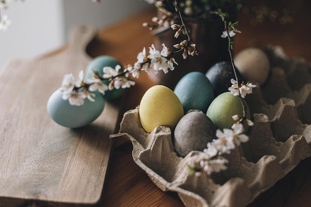Szczęśliwych Wielkanocy Wielkanocni jajka na nieociosanym stole z wiśniowymi kwiatami Naturalni barwiący kolorowi jajka w zasobniku