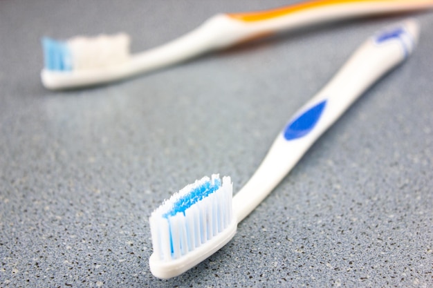 Szczoteczki do zębów osobiste akcesoria na niebieskim zlewie stole Zbliżenie szczoteczek do zębów