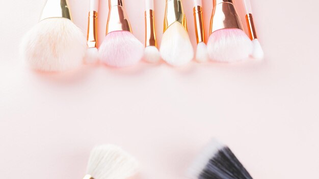 Zdjęcie szczoteczki makijażowe na różowym tle zestaw złotych szczoteczek makijażowych koncepcja kobiecy akcesorium piękno