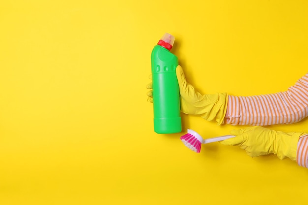 Zdjęcie szczotka i środek dezynfekujący w kobiecych rękach w rękawiczkach na kolorowym tle