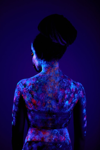 Szczupła czarna kobieta z luminescencją, fluorescencją, body art na ciemnym tle