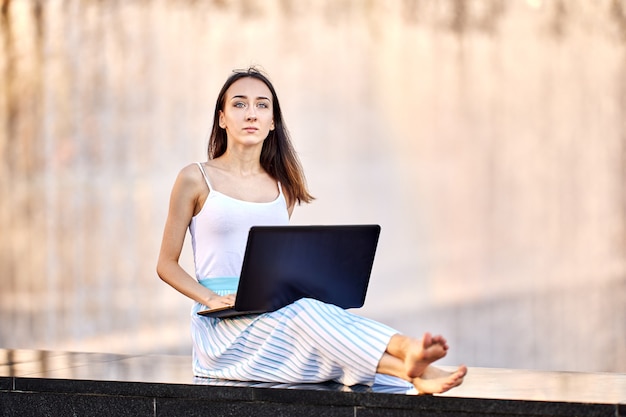 Szczupła kobieta ma e-learning korzystający z laptopa na zewnątrz