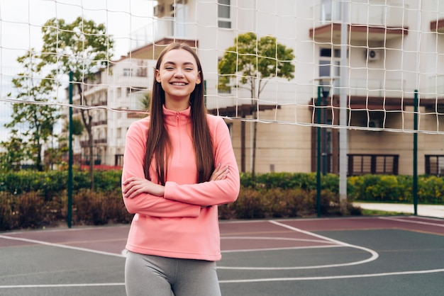 Szczupła młoda dziewczyna w stroju sportowym trenuje i ćwiczy z uśmiechem