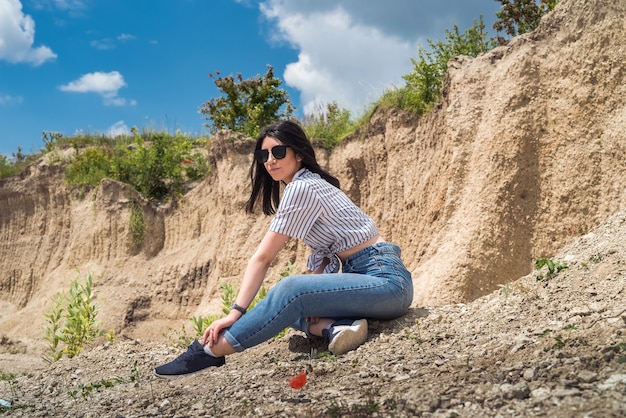 Szczupła młoda kobieta stojąca na piasku w pobliżu skały w kamieniołomie lub kanionie. letni czas na idealną podróż