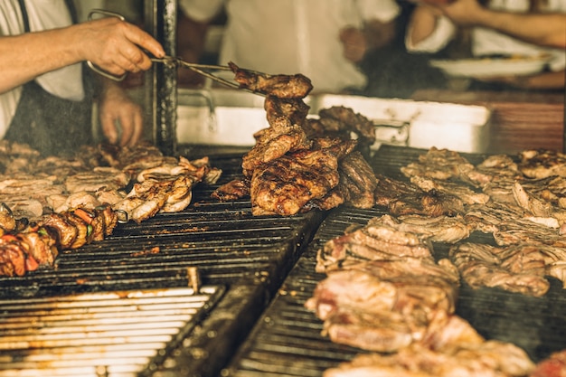 Szef kuchni bez twarzy przygotowujący i gotujący kawałki mięsa na grillu w restauracji.