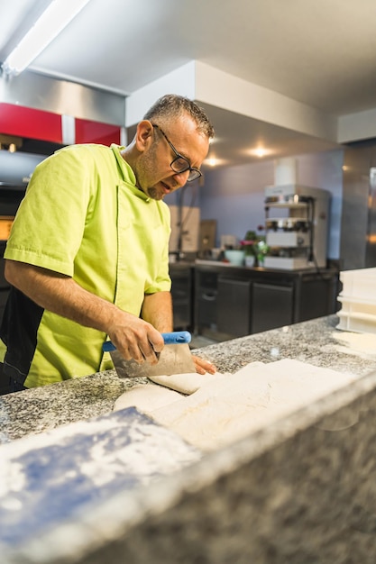 Zdjęcie szef kuchni cięcie ciasta w kulki proces pracy w kuchni pizzę koncepcję