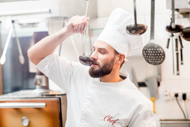 Zdjęcie szef kuchni degustujący jedzenie z dużą gałką w kuchni restauracji