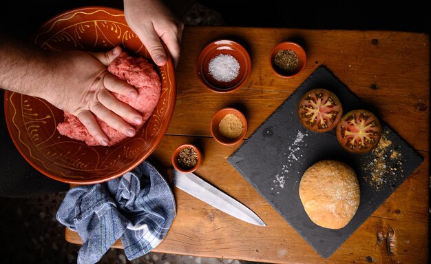 Szef kuchni gotuje kotlety, klocki mięsne lub domowe hamburgery, dodając przyprawy i sól do mięsa mielonego