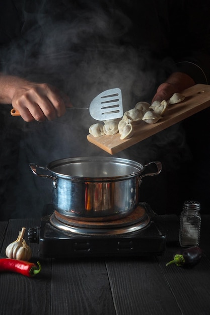 Szef kuchni gotuje pierogi z mięsem w rondlu w kuchni restauracji