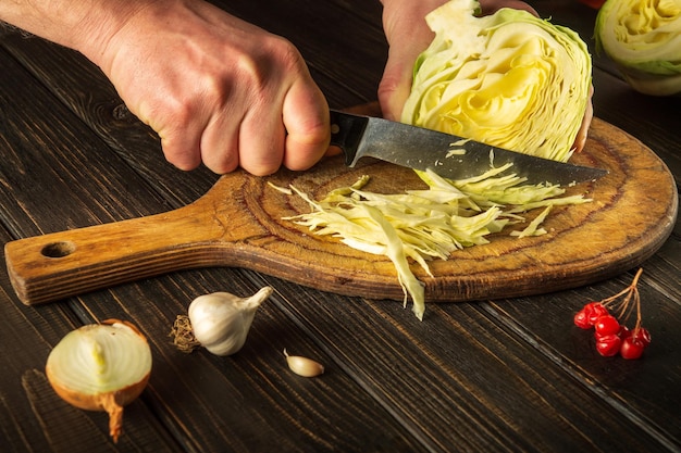 Szef kuchni kroi kapustę nożem Gotowanie sałatki warzywnej na desce do krojenia