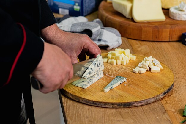 Zdjęcie szef kuchni kroi ser parmezan na desce w kuchni koncepcja kolekcji serów i śródziemnomorskich delikatesów