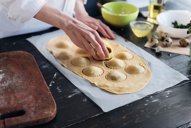 Szef kuchni krok po kroku przygotowuje ravioli z serem ricotta, żółtkami przepiórczymi i szpinakiem z przyprawami. Szef kuchni tworzy ravioli