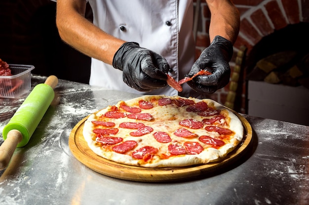 Szef kuchni kucharz robi pyszną pizzę w restauracji z bliska