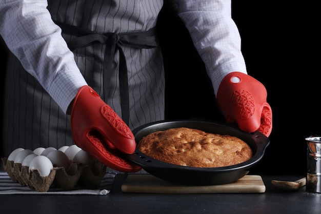 Zdjęcie szef kuchni podaje ciasto na ciemnym tle