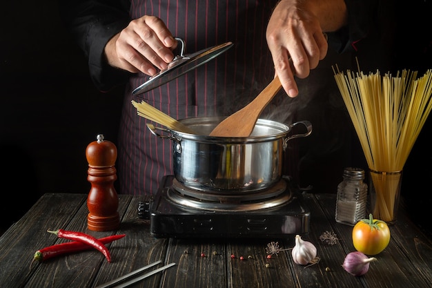 Szef kuchni przygotowuje ekologiczny makaron w gorącym garnku w kuchni Przepis na pyszne jedzenie w hotelu Tradycyjna kuchnia włoska