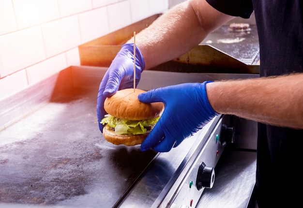 Zdjęcie szef kuchni przygotowuje hamburgery przy kuchennym grillu kuchennym. restauracja.