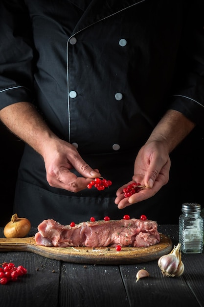 Szef kuchni przygotowuje mięso do pieczenia w kuchni restauracji