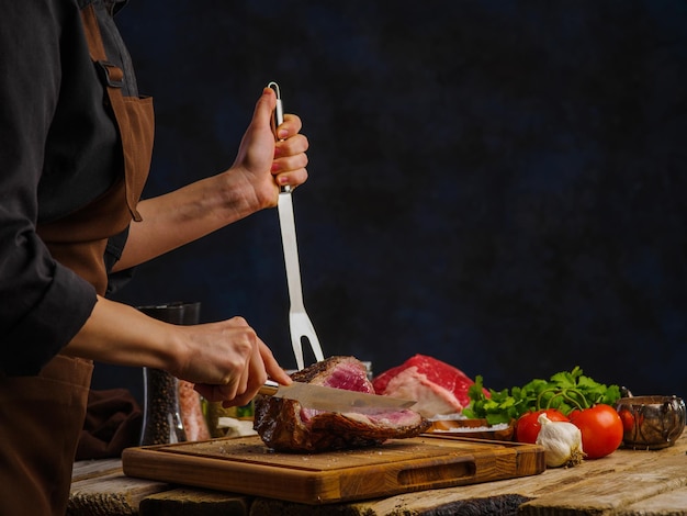 Szef kuchni przygotowuje mięso wołoweRęce szefa przygotowują stek lub szynkę i dodają sól i pieprz