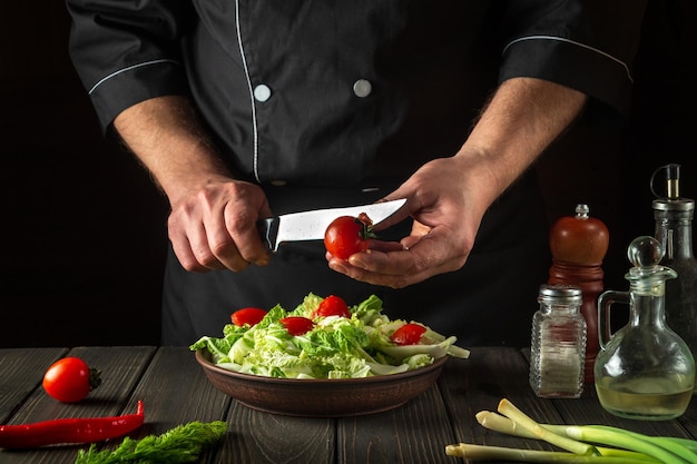 Szef kuchni przygotowuje sałatkę warzywną w kuchni restauracji