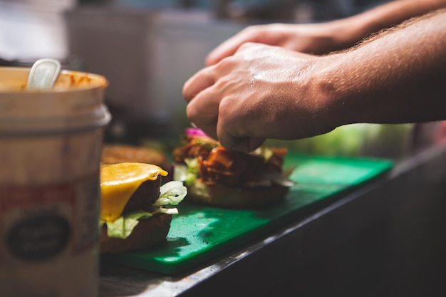 Szef kuchni przygotowuje świeżego soczystego burgera