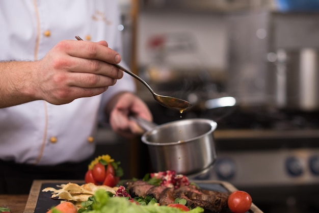 Szef kuchni ręcznie wykańcza talerz stek z w końcu sosem do naczyń i prawie gotowy do podania przy stole?