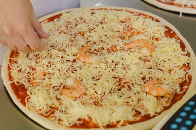 Szef kuchni robi pizzę z owocami morza w kuchni Włoski tradycyjny posiłek z serem i krewetkami