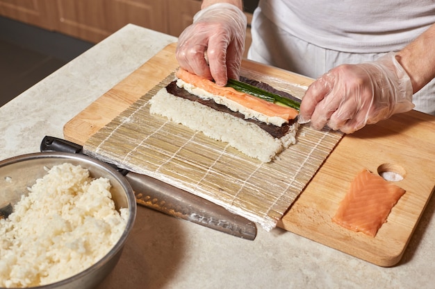 Szef kuchni robi sushi. Przygotowanie bułek z łososiem